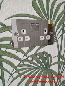 Chrome LAP socket installed in a wall with leaf pattern paper